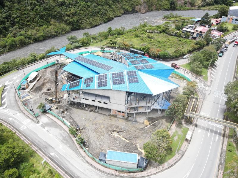 Edificio de tres plantas con techo azul en construcción en medio de una rotonda.
