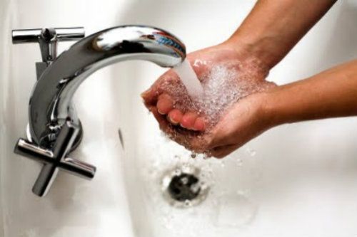 Persona lavandose las manos en un lavamanos.