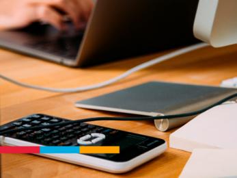 Escritorio con equipos de computo y una calculadora