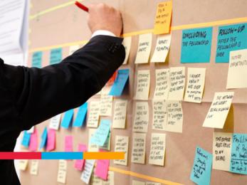 Persona agregando postit en una pared.