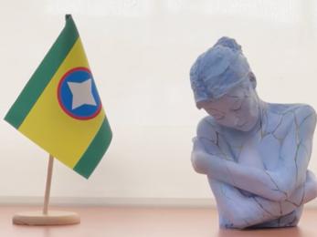 Bandera de Bucaramanga al la do de una escultura sobre un escritorio.