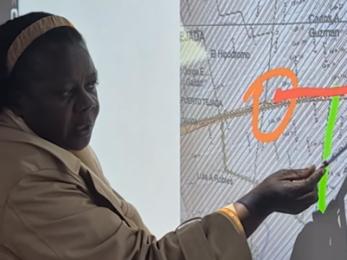 Mujer señalando algunos sectores en un mapa.